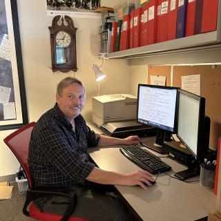 Stephen Davies sits at his computer with a digitized letter on the screen