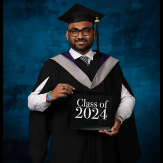 Ashutosh Mishra in his grad regalia holding a Class of 2024 sign.