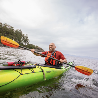 Farhad Moghimefar paddling a kayak and smiling off into the distance