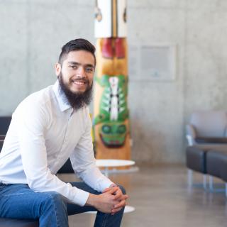 Fernando sits near the totem inside the Centre for Health and Science, VIU's Nanaimo campus