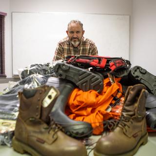 Mike with boots, waterproof jackets and waders laid out on a table