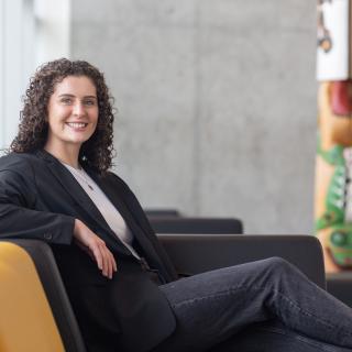 Kayla Passmore sits on a couch in front of the totem in the Centre for Health and Science atrium