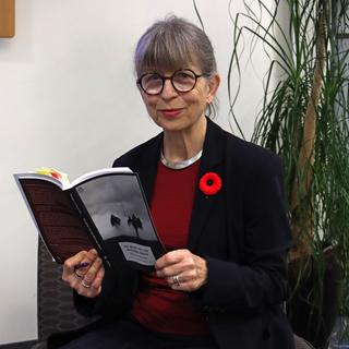 Katharina wears a poppy and holds a copy of her translation of All Quiet on the Western Front