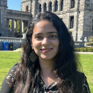 Harleen Kalra standing outside on a sunny day and smiling at the camera.