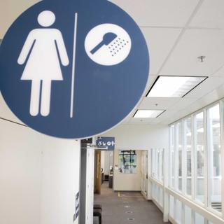 A bathroom sign indicating a female bathroom with a shower.