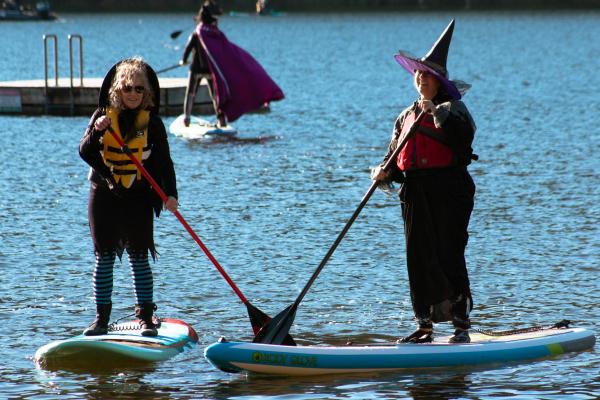 Two women dressed as witches paddle on Westwood Lake