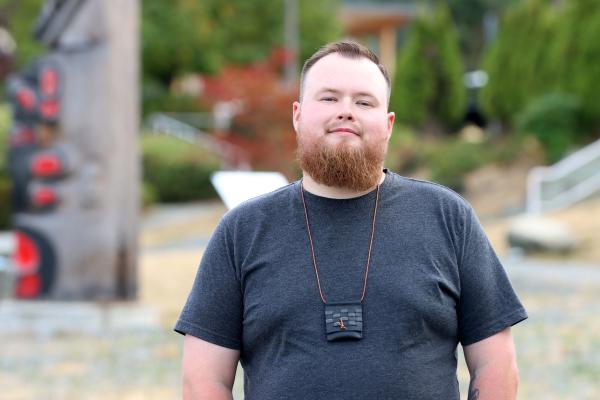 Portrait of Aaron Moore in front of totems at VIU Nanaimo campus