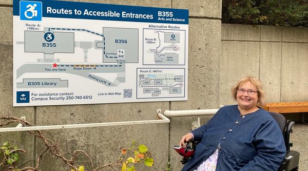 A woman poses beside a wayfinding sign at VIU's Nanaimo campus