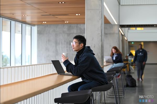 Jiayi Li sitting at a table with a cup of coffee looking out the window