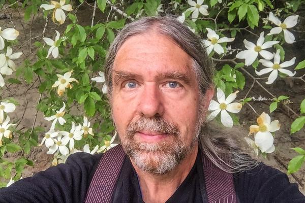 Craig Evans standing in front of some white flowers