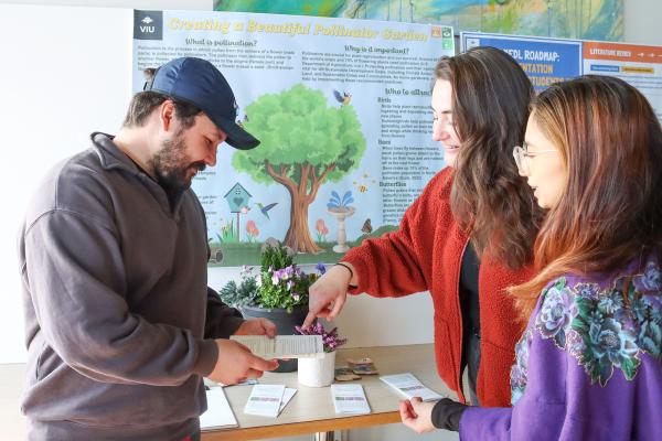 Three students next to a poster explaining research