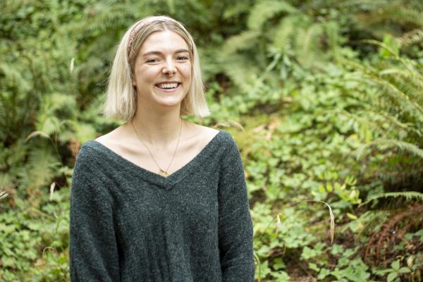 Denman Moody smiles while standing in front of green ferns.