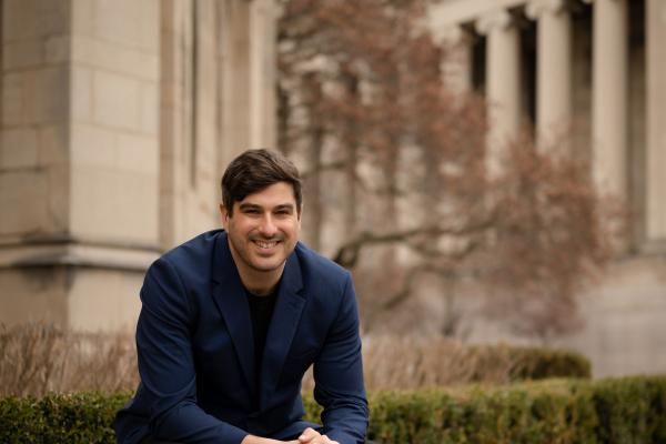 Michael MacKenzie sits on a bench in front of a stone building