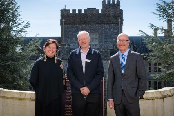 Three people standing in front of Royal Roads University