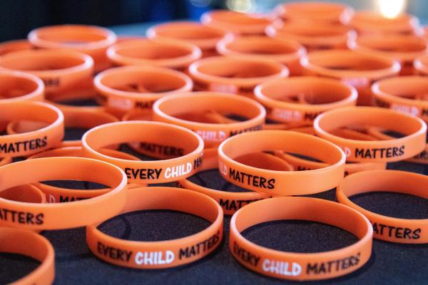 Dozens of orange bracelets that read Every Child Matters