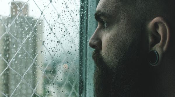 Man staring out the window at the rain