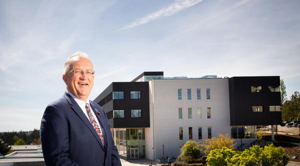 Ralph Nilson, former VIU president, smiles with the Dr. Ralph Nilson Centre for Health and Science in the background