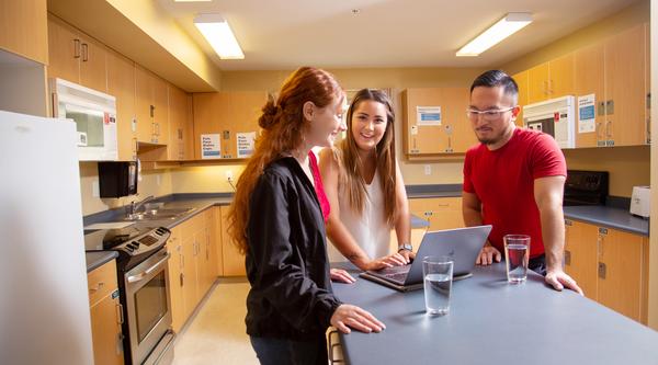 Three students standing around a kitchen island