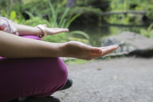 A woman meditates on a wooden bench next to a koi pond at Vancouver Island University