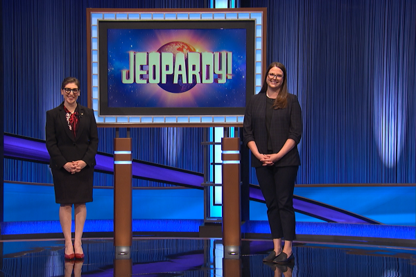 Whitney Wood stands on the Jeopardy! stage with host Mayim Bialik.