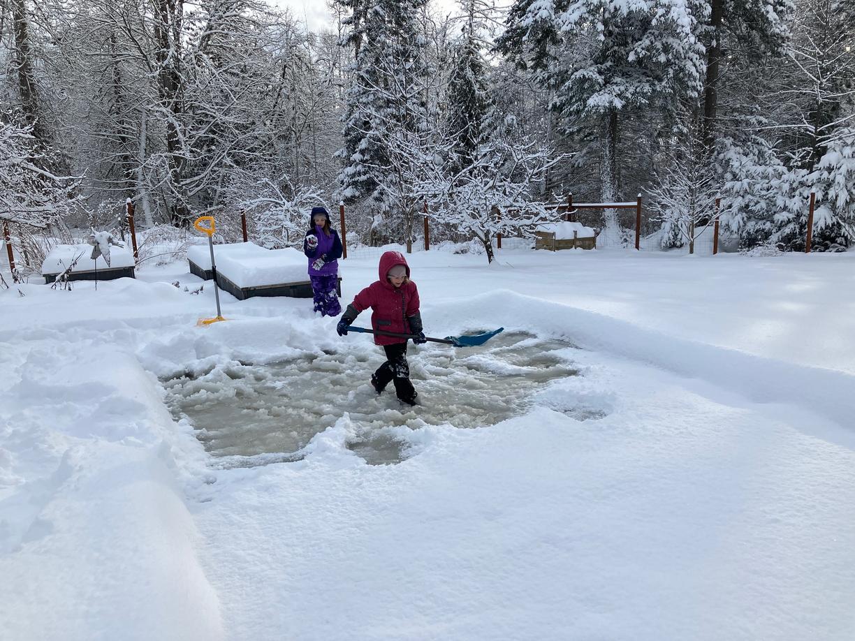 Children on a rink clearing the snow off