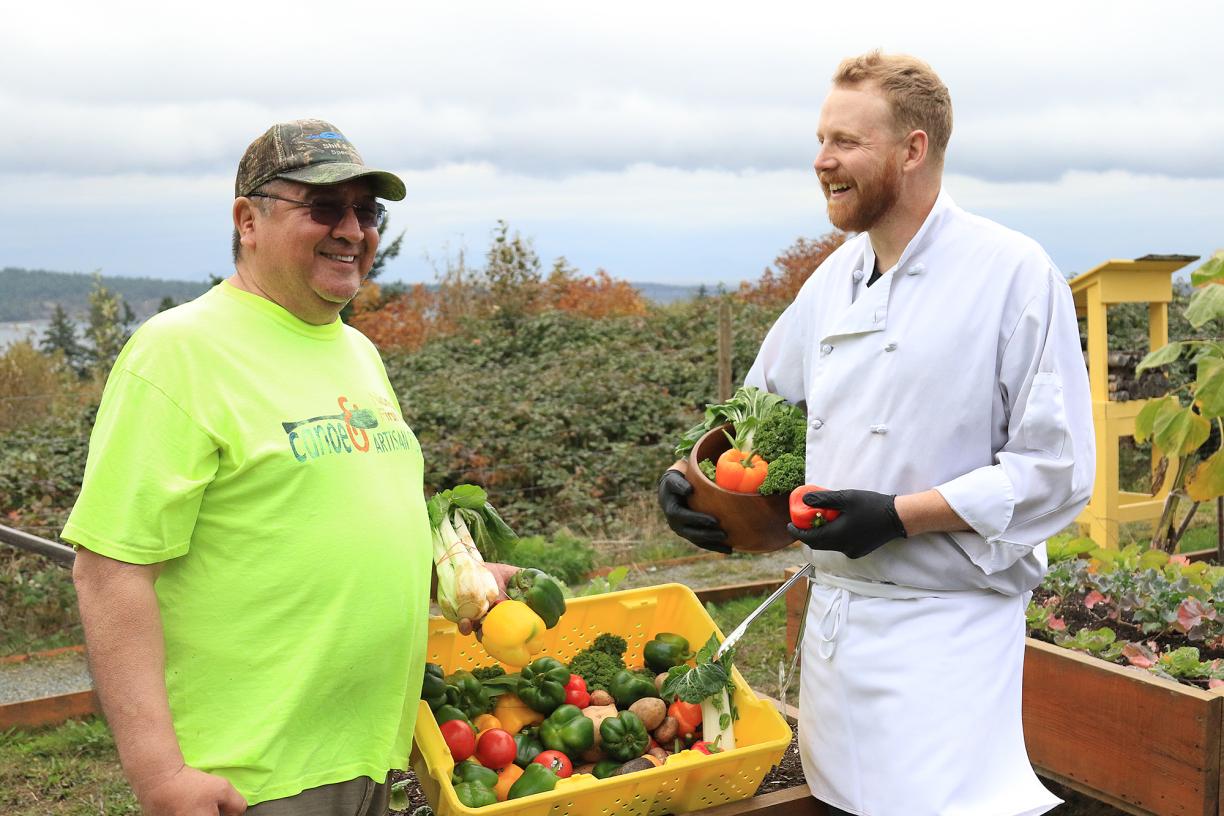 James Cook, left, a volunteer for the Loaves and Fishes Food Bank and Sean Weins, Garden Café Chef, share stories in the Snaw-Naw-As Health Centre’s Garden of Spiritual Healing. 