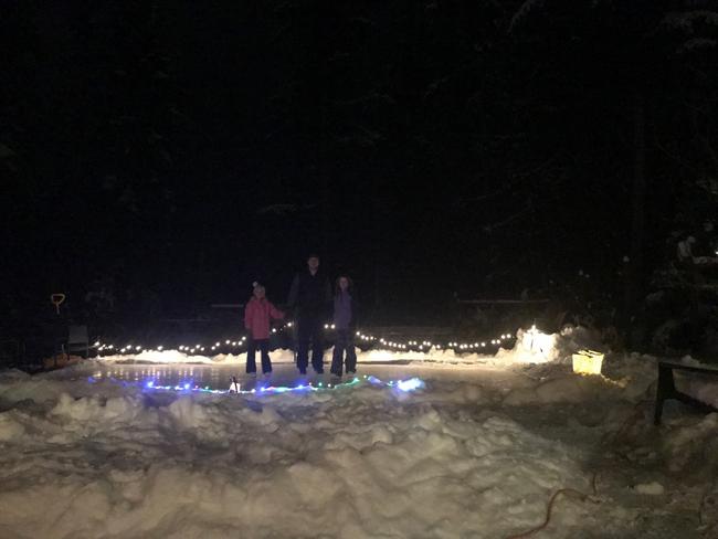 A backyard skating rink in the dark with lights around it