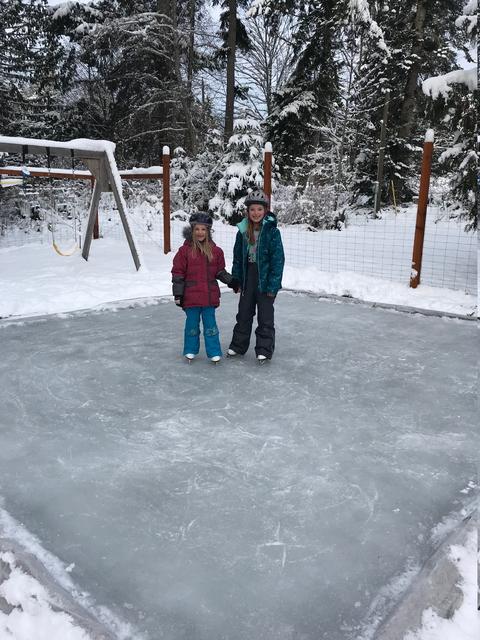 Two children standing on an ice rink