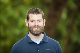 Dr. Jamie Gorrell stands in front of a cropping of trees at VIU's Nanaimo campus