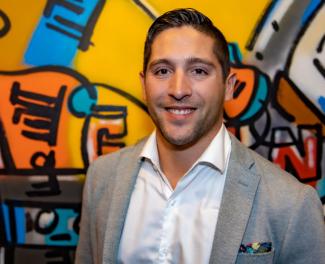 Man smiling in front of colourful background