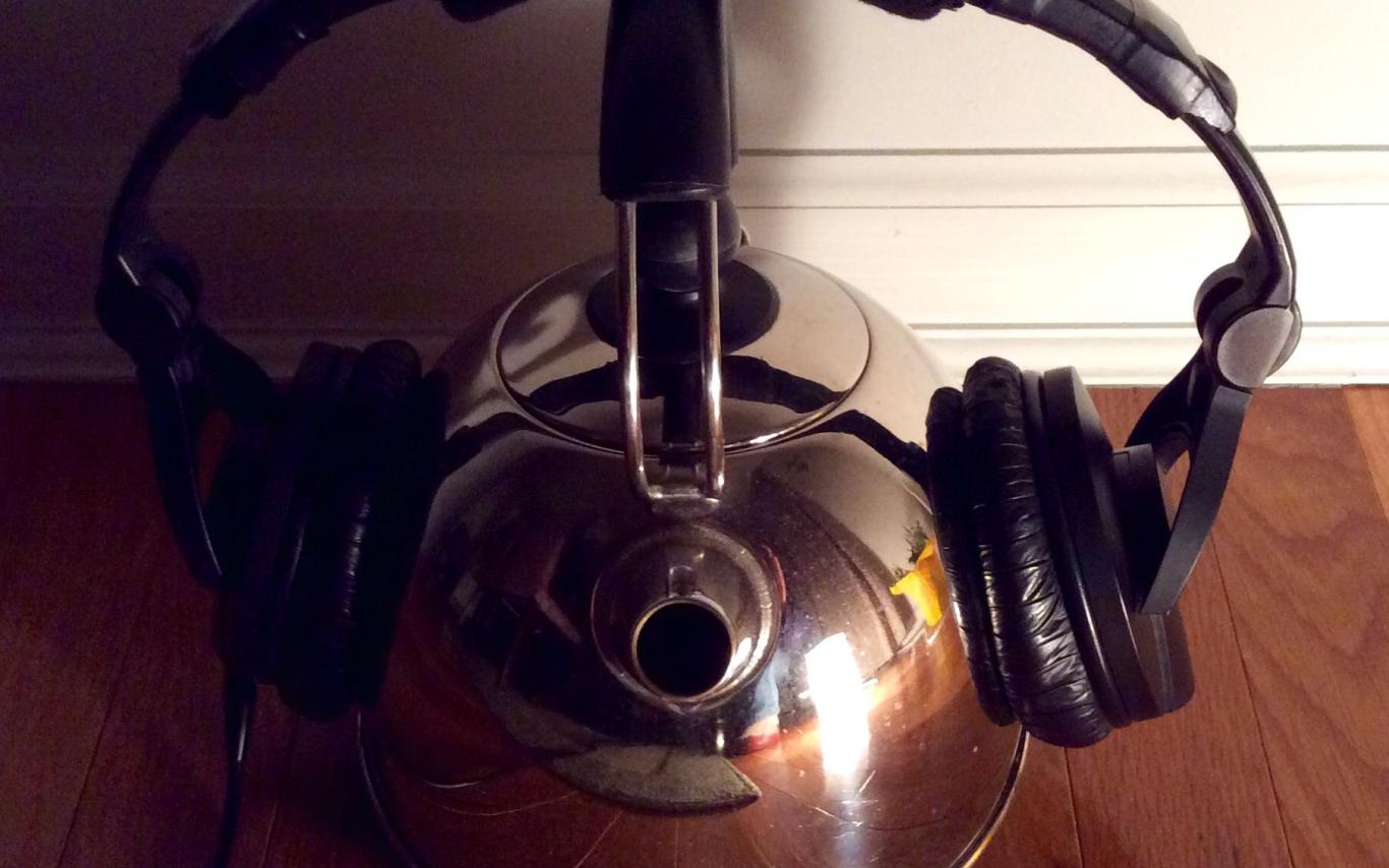 Headphones resting on a tea kettle.