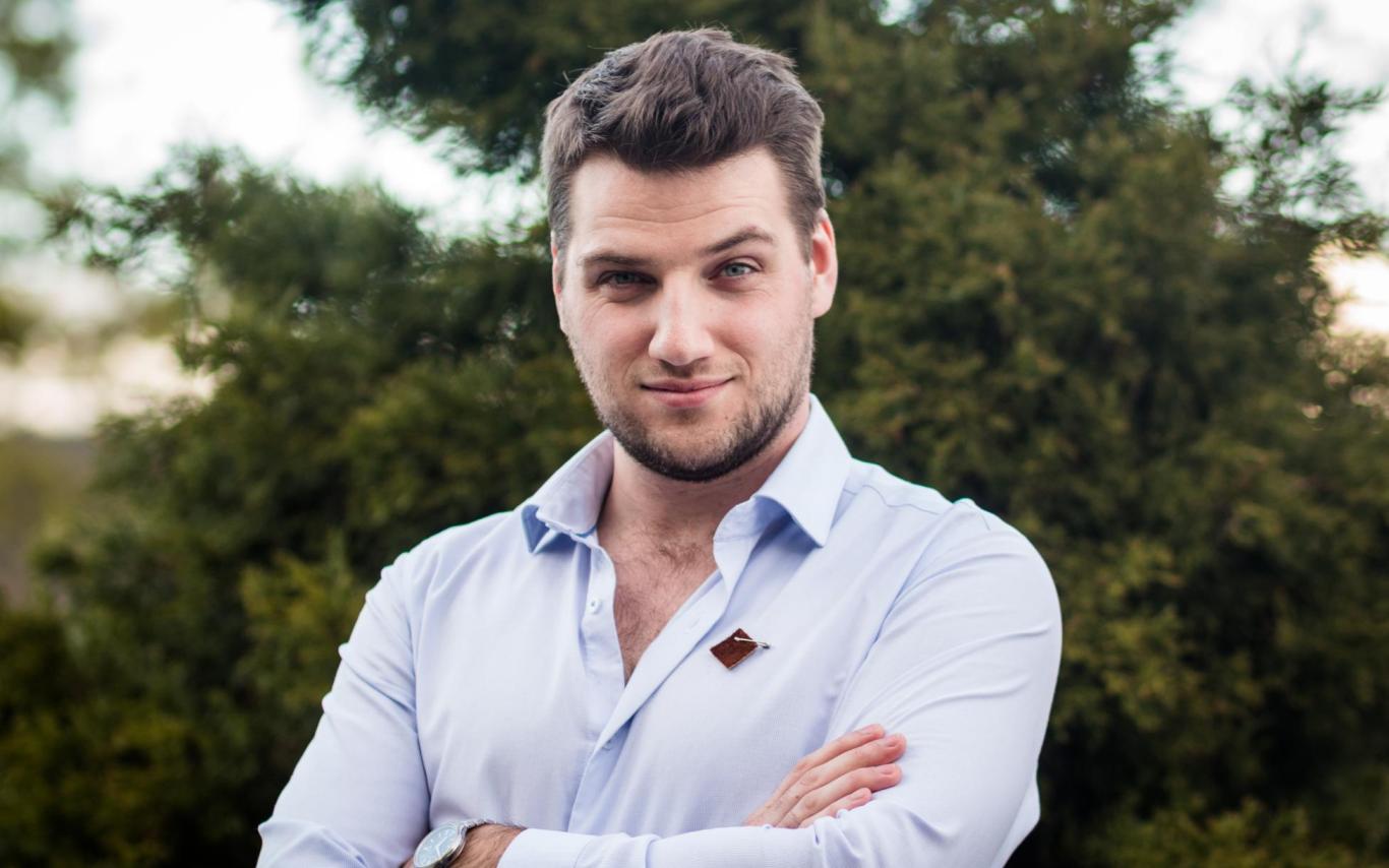 Portrait of Jonah with arms crossed in front of greenery
