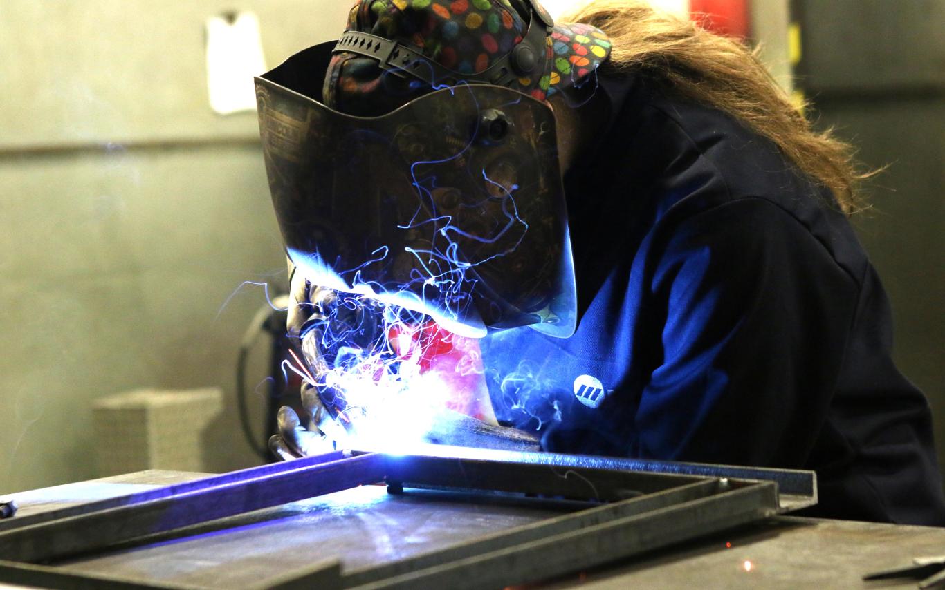 Head and shoulders of Sarah with a painting of ships behind her