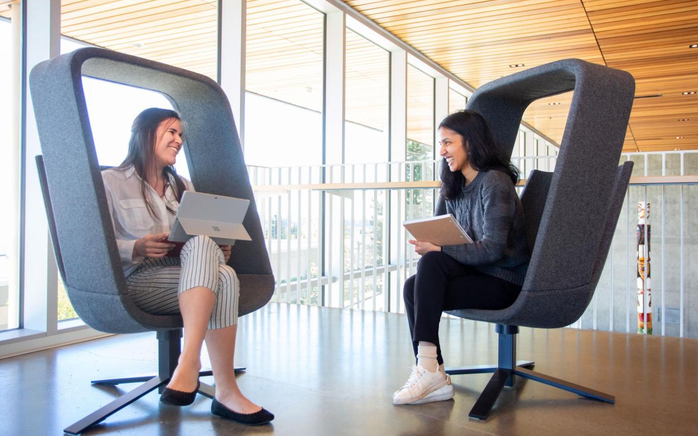 Two students interact while sitting in chairs